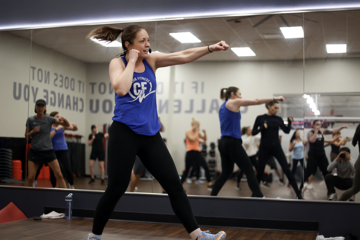 English teacher Cheryl Ogolin stands in front of her kickboxing class as she leads a workout. Ogolin has been kickboxing for over 12 years. “[The class] is about me, the instructor, looking out and seeing what my participants are doing,” Ogolin said. “I give them real, live feedback, but also coach them through the move.” (Photo by Lathan Levy)
